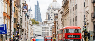 People walking on a busy street in London, England near St. Paul's Cathedral.